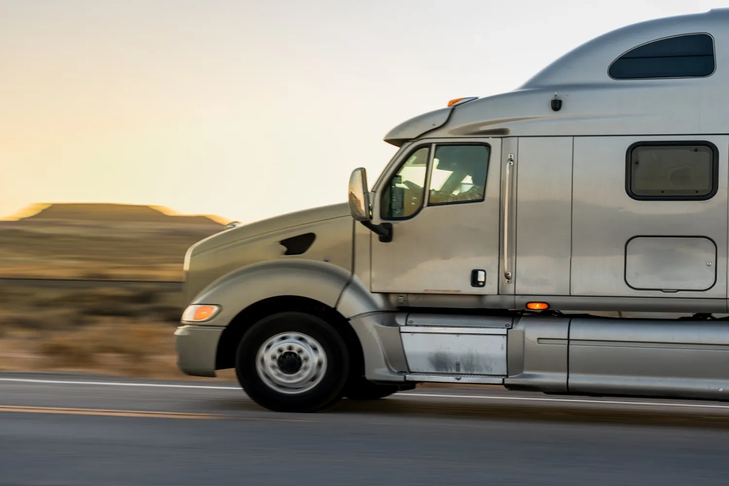 Grey semi truck driving on road in desert